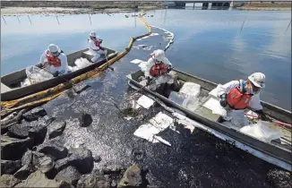  ?? Ringo H.W. Chiu / Associated Press ?? Cleanup contractor­s deploy skimmers and floating barriers known as booms to try to stop further oil crude incursion into the Wetlands Talbert Marsh in Huntington Beach, Calif., on Sunday.