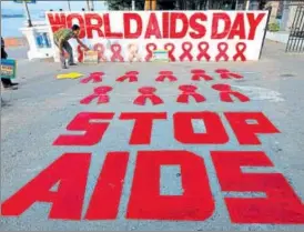  ?? REUTERS ?? A man places a placard during an awareness campaign organised on the eve of World AIDS Day in Kolkata on Thursday.