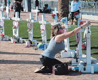  ?? ETHAN MILLER GETTY IMAGES ?? : Ashley Schuck of Nevada places a medal she got for running for shooting victim Neysa Tonks in Saturday's Vegas Strong 5K on a cross set up for Tonks on Oct. 1in Las Vegas, Nevada.