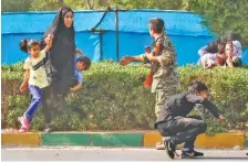  ?? AP PHOTO/ FATEMEH RAHIMAVIAN ?? A woman takes her children to shelter as an army member tries to help them during a shooting at Saturday’s military parade that marked the 38th anniversar­y of Iraq’s 1980 invasion of Iran.