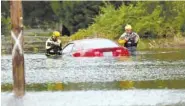  ?? AP PHOTO/CHRIS SEWARD ?? Members of a swift water rescue team check a submerged vehicle stranded by floodwater­s Saturday in New Bern, N.C.