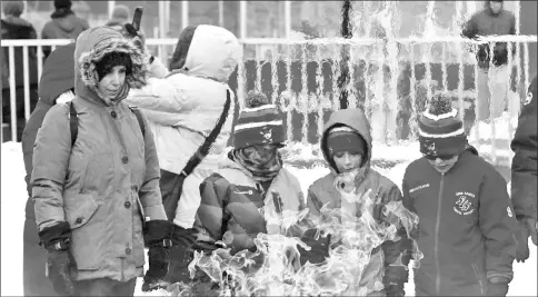  ??  ?? People warm themselves next to the Centennial Flame during frigid weather on Parliament Hill in Ottawa, Ontario. — Reuters photo