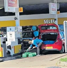  ?? ?? A motorist fills several petrol containers in Upminster, Essex In defiance of official pleas