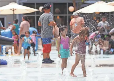  ?? PATRICK BREEN/THE REPUBLIC ?? Children play in the splash pad at CityScape in Phoenix in July.