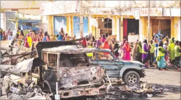  ??  ?? Worshipper­s walk past shells of destroyed vehicles in the centre of Mogadishu