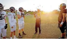  ??  ?? Official Harold Hill, center, flips a coin before a high school football game between Edmond Memorial and Westmoore.