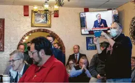  ?? Justin Rex / Associated Press ?? Gov. Greg Abbott delivers the mask announceme­nt, broadcast on the TV in the background, as a crowd watches him make it at a Mexican restaurant in Lubbock.