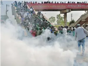  ?? TONY KARUMBA/AFP/Getty Images ?? Students from Langata Road Primary School flee up a bridge Monday to escape tear gas as police attempt to break up a demonstrat­ion against the removal of the school’s playground.
Police later said the officer in charge at the scene has been suspended.