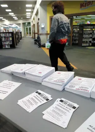  ?? The Sentinel-Record/Richard Rasmussen ?? A patron walks past a table with tax forms and AARP Tax-Aide flyers at the Garland County Library on Thursday.