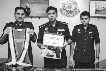  ??  ?? Chandra (centre) and other police officers showing the fake replica pistol and enforcemen­t vest.