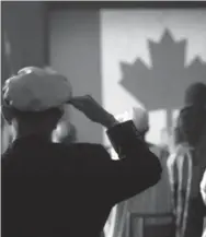  ?? TIM KROCHAK/CANADIAN PRESS ?? A merchant seaman salutes the Canadian flag during the singing of “O Canada” at a citizenshi­p hearing in Halifax.