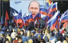  ?? Associated Press ?? IN SEVASTOPOL in Crimea, people wave Russian f lags while watching Vladimir Putin deliver a speech after the leader said he’d annexed four regions of Ukraine.