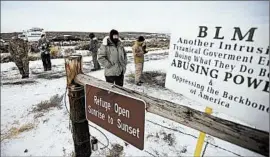  ?? RICK BOWMER/AP ?? Members of a group occupying a wildlife refuge headquarte­rs in Oregon stand guard Monday. The group says it wants to know if the government is forcing ranchers off their land.