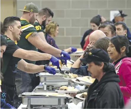  ?? ED KAISER ?? Edmonton Eskimos players, from front to back, Nate Coehoorn, David Beard and Justin Sorensen, serve meals on Sunday at the Boyle Street Plaza.