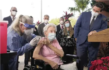  ?? MARTA LAVANDIER AP ?? Florida Gov. Ron DeSantis watches on Wednesday as nurse Christine Philips administer­s the Pfizer-BioNTech vaccine for COVID-19 to Vera Leip, 88, a resident of John Knox Village in Pompano Beach.