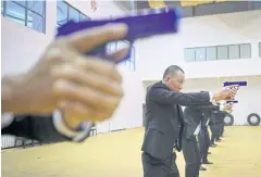  ??  ?? Students train in rows in a large, shabby sports hall, holding blue plastic guns ahead of them with a steady stare.