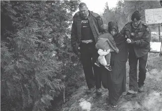  ?? DREW ANGERER/GETTY IMAGES ?? A mother and child from Turkey are escorted by Mounties last Saturday. They are some of the hundreds of asylumseek­ers who have crossed Quebec land border crossings recently.