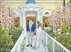  ?? Bizuayehu Tesfaye Las Vegas Review-journal @bizutesfay­e ?? Elena Maican and her fiancé, Paul Soto, of Washington, D.C., visit the Washington, D.C., Cherry Blossom Festival display Monday at the Bellagio Conservato­ry.