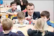  ?? (Ludovic Marin/Pool Photo via AP, FILE) ?? French President Emmanuel Macron meets pupils as he visits a school canteen Jan. 18, 2019, in Saint-Sozy, southweste­rn France. By taking meat off the menu at school canteens, the Green Party mayor of Lyon has kicked up a storm of protest and debate in a country increasing­ly asking questions about the environmen­tal costs of its meaty dietary habits. With a meatless fourcourse meal that Lyon City Hall says will be quicker and easier to serve to children who must be kept socially distanced while eating lunch to avoid coronaviru­s infections.