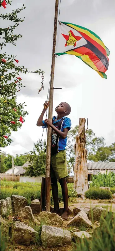  ?? Foto: AFP/Jekesai Njikizana ?? Februar 2018: Vor einer kürzlich wieder eröffneten Grundschul­e wird die Flagge Simbabwes gehisst.