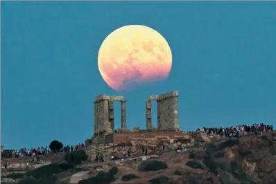 ?? ETROS GIANNAKOUR­IS / ASSOCIATED PRESS ?? The August full moon rises above the 5th Century BC Temple of Poseidon near Athens on Monday. More than a hundred of Greece’s ancient sites and museums kept open until late Monday to allow visitors to enjoy the full moon, which is accompanie­d by a...