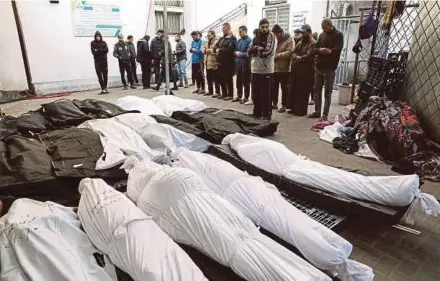  ?? REUTERS PIC ?? Mourners praying near the bodies of Palestinia­ns, most of whom were killed in Israeli strikes, at Abu Yousef Al-Najjar Hospital in Rafah, southern Gaza Strip, yesterday.