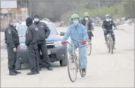  ?? DARKO VOJINOVIC — THE ASSOCIATED PRESS ?? Vietnamese workers who are helping construct the first Chinese car tire factory in Europe ride b icycles past security officers near the northern Serbian town of Zrenjanin on Thursday.