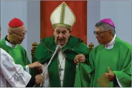  ?? NG HAN GUAN — THE ASSOCIATED PRESS ?? Pope Francis is joined assisted by Cardinal John Tong Hon, left, and Cardinal-elect Stephen Chow, both from Hong Kong, after presiding over a Mass at the Steppe Arena in the Mongolian capital of Ulaanbaata­r on Sunday.