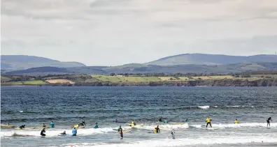  ??  ?? Surfers ride the waves at Rossnowlag­h, Ireland. The long sandy beach there is a popular spot for beginner and intermedia­te surfers.