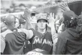  ?? WILFREDO LEE/AP ?? JT Realmuto gets congratula­ted by teammates after he scored on a ground-out by Starlin Castro.