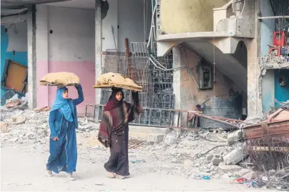  ?? Picture: AFP ?? FOOD OF LIFE. Women yesterday carry bread past a building damaged by the Israeli bombardmen­t in Rafah in the southern Gaza Strip as the war with Palestinia­n militant group Hamas continues.