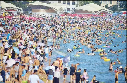  ?? AFP ?? People cool off on a beach amid high temperatur­es in Qingdao, in east China’s Shandong province on Monday.