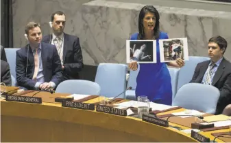  ?? Drew Angerer / Getty Images ?? U.S. Ambassador to the United Nations Nikki Haley holds up photos of victims of the apparent chemical attack in Khan Sheikhoun, Syria, during a meeting of the U.N. Security Council.