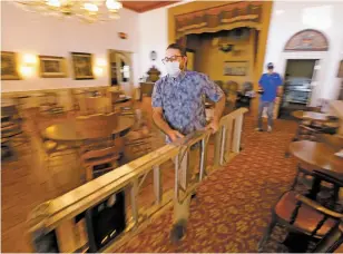  ?? PHOTOS BY LUIS SÁNCHEZ SATURNO/THE NEW MEXICAN ?? Sean Sinclair, operator and chef of the Legal Tender Saloon and Eating House, carries a ladder to replaces a bulb on one of the chandelier­s Monday. The eatery opens Saturday in Lamy.