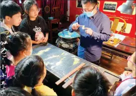  ?? ?? Hou demonstrat­es the gold lacquer inlaying technique for students in Beijing.