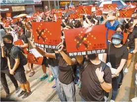  ?? AP-Yonhap ?? Protestors display anti-China placards in Hong Kong, Sunday. Riot police fired tear gas after a large crowd of protesters at a Hong Kong shopping district ignored warnings to disperse in a second straight day of clashes, sparking fears of more violence ahead of China’s National Day.