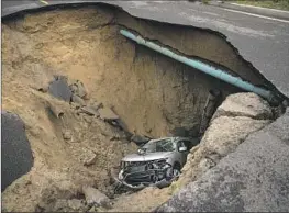  ?? Jason Armond Los Angeles Times ?? A SINKHOLE swallowed two cars Jan. 10 in Chatsworth. The weight of traffic creates cracks in asphalt that admit water, weakening the sub-base and soil.