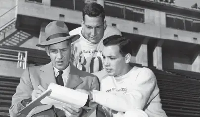  ?? THE COMMERCIAL APPEAL ?? Mississipp­i State assistant coach C.M. Strange discusses plans with Jack Blount, center, of Memphis and John Tulloh of Keystone, W. Va., on Nov. 9, 1951, for their game with Memphis State at Crump Stadium the following day.