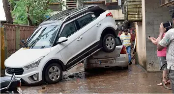  ?? — MRUGESH BANDIWADEK­AR ?? A car is seen piled over another, presumably after being drifted by floodwater during Tuesday’s heavy downpour, at Borivali in Mumbai on Wednesday.