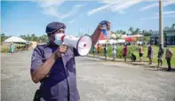  ?? — AFP ?? A police officer directing residents waiting in line for Covid-19 testing in Fiji’s capital Suva, amid a worsening outbreak of the Delta variant in the South Pacific nation.