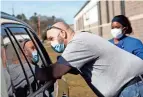  ??  ?? Rick Lanuzza, a paramedic with the Fredrickto­wn Fire Department, talks to a patient receiving a vaccinatio­n while LPN Dejah Bennett takes notes at the drive-up vaccinatio­n area outside of the Mount Vernon Energy Fieldhouse.