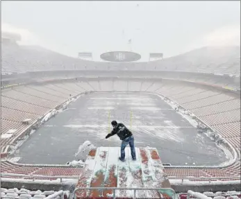  ?? Ed Zurga / Associated Press ?? Kyle Haraugh, of NFL Films, clears snow from a camera location at Arrowhead Stadium before an NFL divisional football playoff game between the Kansas City Chiefs and the Indianapol­is Colts, in Kansas City, Mo., Saturday. About eight inches had fallen by kickoff.The storm has caused the death of at least five people because of crashes on slick roadways in Kansas and Missouri.