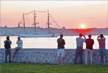  ?? SEAN D. ELLIOT/THE DAY ?? Spectators gather along Shore Avenue in Groton to watch and take photos Thursday as the U.S. Coast Guard barque Eagle enters New London Harbor just as the sun sets. Eagle has been across the Atlantic training Coast Guard Academy cadets all summer and is back in its home port of New London to exchange third-class cadets for swabs before it departs again to finish out the summer training schedule.