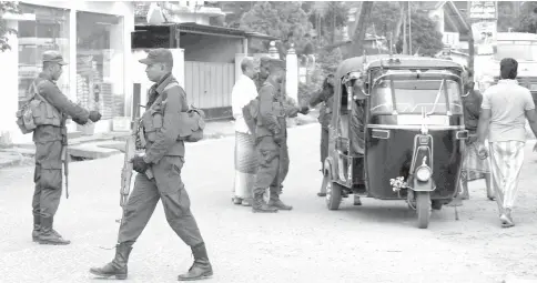  ?? — AFP photo ?? Sri Lankan security personnel inspect a three-wheeler rickshaw at a checkpoint on a roadside in Minuwangod­a.