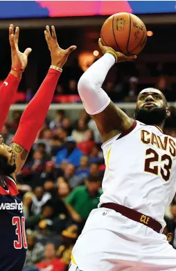  ?? (Reuters) ?? CLEVELAND CAVALIERS forward LeBron James takes an off-balance shot over Washington Wizards defender Mike Scott in the first half of the Cavs’ road victory over the Wizards on Sunday night in which James finished with 20 points, 12 rebounds and 15...