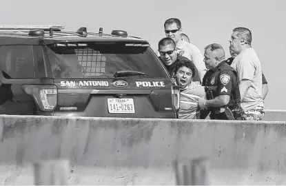  ?? Kin Man Hui / Staff photograph­er ?? A man kept police at bay for hours Tuesday on an overpass of Interstate 35 near Zarazamora, threatenin­g to take his life. The incident forced both the northbound and southbound lanes to be shut down in the area, and traffic was diverted for about four hours as police negotiated with him. The situation ended after police were able to lure the man away from the ledge and subdue him. The man still appeared agitated and was yelling until they placed him into a waiting ambulance.