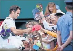  ??  ?? FAVORITO. Roger Federer firma autógrafos en Wimbledon.