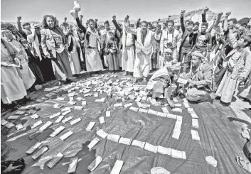  ?? — AFP photo ?? Yemeni tribesmen chant slogans as they stand around men counting wads of Yemeni rial cash bills during a tribal meeting in the Huthi rebel-held capital Sanaa, as tribes donate rations and funds to fighters loyal to the Huthis along the fronts.