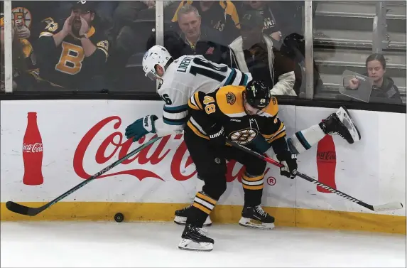  ?? STAFF PHOTO BY NANCY LANE — BOSTON HERALD ?? Boston Bruins defenseman Matt Grzelcyk checks San Jose Sharks center Steven Lorentz into the boards during the third period of a Jan. 22 game at the TD Garden.