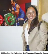  ?? ?? Hidilyn Diaz, the Philippine­s' first Olympic gold medalist, beside the iconic photograph capturing her triumphant moment by Agence France-presse (AFP’S) Vincenzo Pinto.